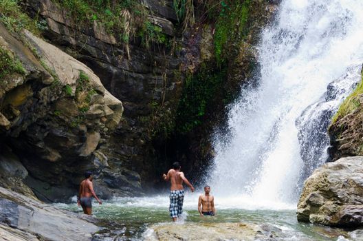 Ella, Sri Lanka - December 09, 2011: Sri Lankian teenagers take a bath in Ravana Falls.  It ranks as one of the widest waterfalls in the country