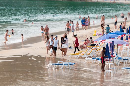 Rawai, Phuket, Thailand - January 19, 2012: View of the Tai beach: tourists, sunbeds and umbrellas