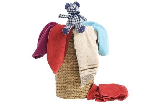 colorful towels in a basket isolated on white background and a resting teddy bear