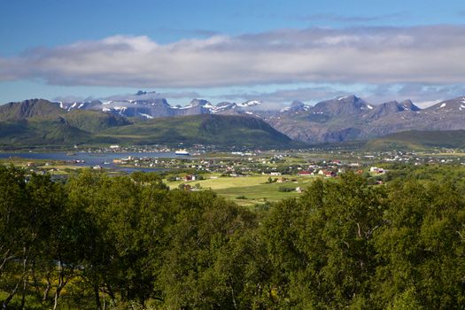 Picturesque panorama on Lofoten from Justadtinden with green lowlands and snowy peaks of mountains