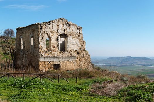 Farmhouse ruin among rural landscape