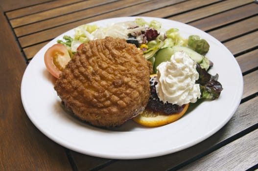 Fried camembert with garnish on a white plate
