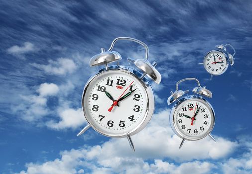 Three alarm clocks flying on blue sky, time flies concept