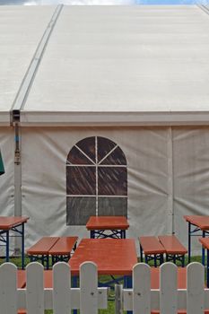 A white party or event tent with beer tables and benches