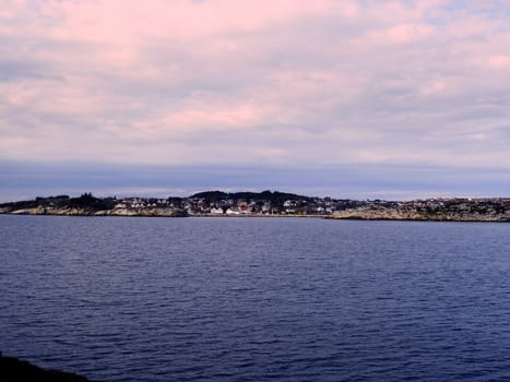 coastline with houses in norway. cloudy sky in evening light
