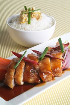 Chicken with rice and vegetables in background