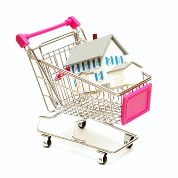 A house sits inside a shopping cart for real estate concepts.