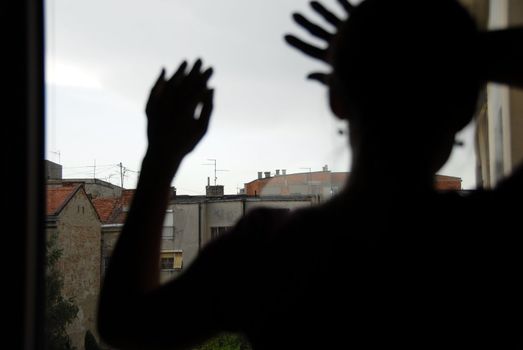 woman black silhouette looking out window indoors, with hands on glass