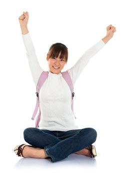Full body excited Asian female young adult student sitting on floor hand raised arms up isolated on white background