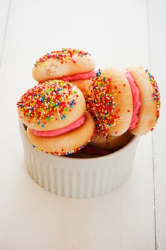 Cookies with strawberry cream covered with sprinkles on white background