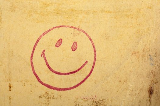 Photo of a vintage happy face stamp on old scratched worn paper.