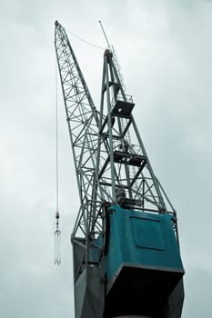 Big crane on quay in port with cloudy sky background