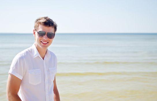 Handsome smiling guy on the beach, with the sea in the background