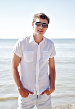 Handsome smiling guy on the beach, with the sea in the background