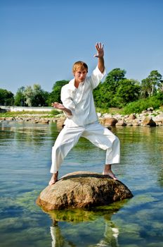 Man in kimono posing on the rock in the sea