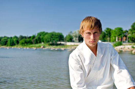 Young man in kimono on sky and sea background