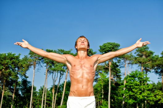 Young man spreading hands on a sky backgroung