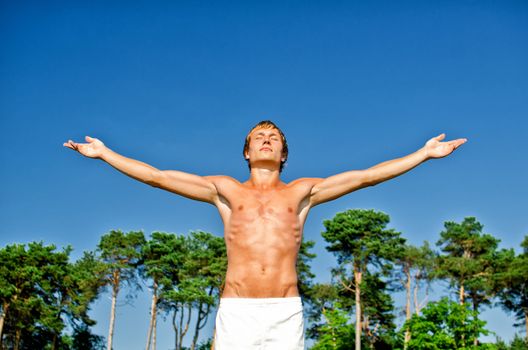 Young man doing meditation exercises on sky background