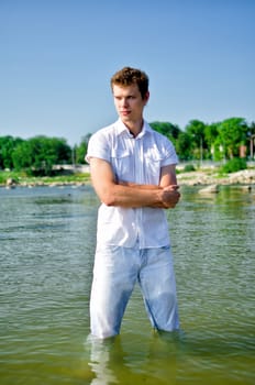 Handsome young guy standing in the sea in jeans