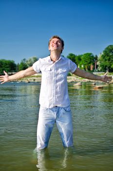 Handsome young guy standing in the sea in jeans