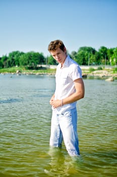 Handsome young guy standing in the sea in jeans