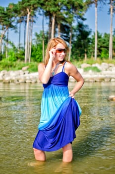 Pretty woman in a long dress posing in the sea