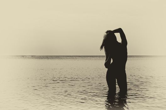 Retro style photo: Silhouette of woman in the sea