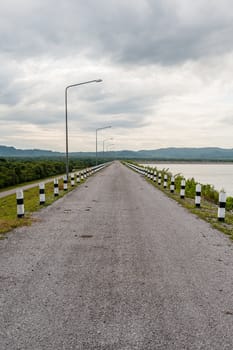 Road to mountain on dam with coud in sky