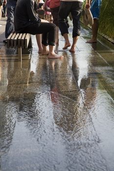 People cooling their feet on a pavement with running water.