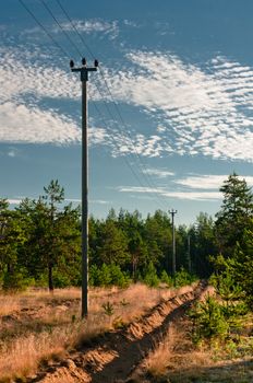 Power lines support at forest outskirts with beautiful cloudscape