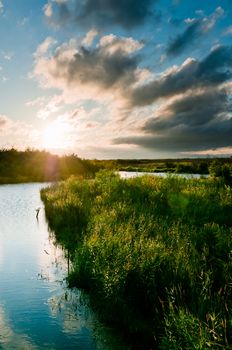 River and land with grass scene with beautiful cloudscape on background