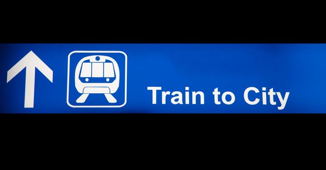 Train to city blue sign in an airport isolated on black