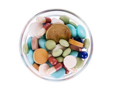 Fifty euro cents in glass saucer full of different pills on white background