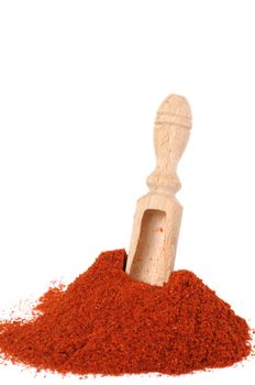 Scoop in heap of red powder pepper on white background with focus on scoop