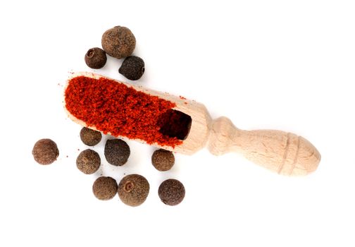 Wooden scoop in heap of pepper with peppercorns of sweet pepper