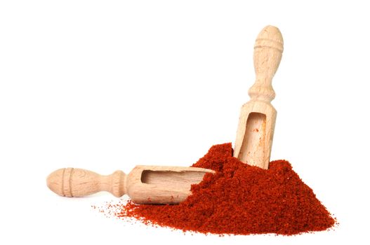 Two wooden scoops in heap of red powder pepper on white background with focus on scoop