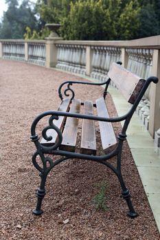 Stylish wooden park bench near stone fence after rain