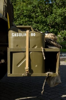 Vintage olive green fuel container, jerrycan, on a rack attached with a webbing strap.