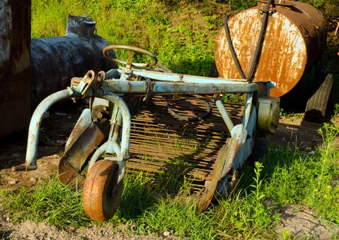 Retro rusty potato digging vehicle. Ancient agricultural machinery.