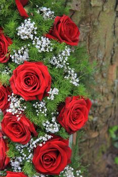 Red roses and white gypsophila in a funeral wreath, detail near a tree