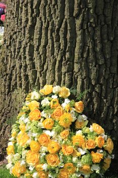 yellow roses and ranunculus in a heart shaped funeral arrangement