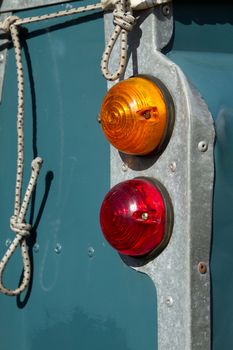 Red brake and amber indicator rear lights with a corner panel and dark blue body work.