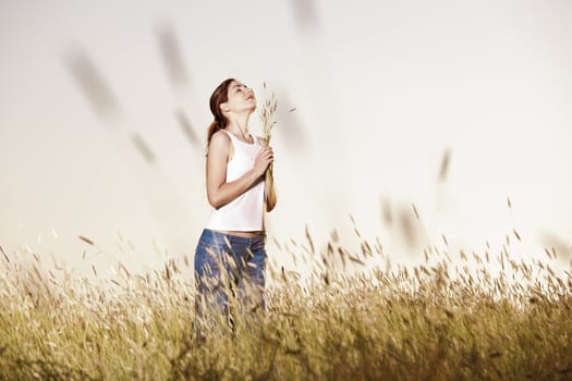 Outdoor portrait of a beautiful woman holding flowers on a summer day