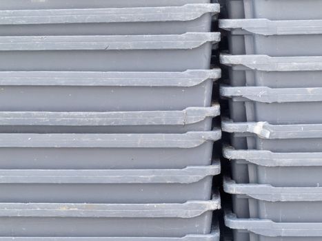 Background texture pattern of stacks of empty grey plastic containers as used in fishery, wholesale, storage of fresh produce, cargo and retail transportation