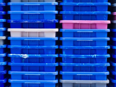 Background texture pattern of stacks of empty colorful plastic containers as used in fishery, wholesale, storage of fresh produce, cargo and retail transportation
