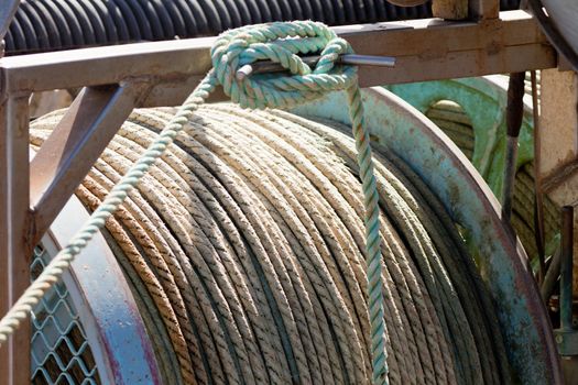 Closeup of drum of old worn hemp rope coils on fishing boat deck
