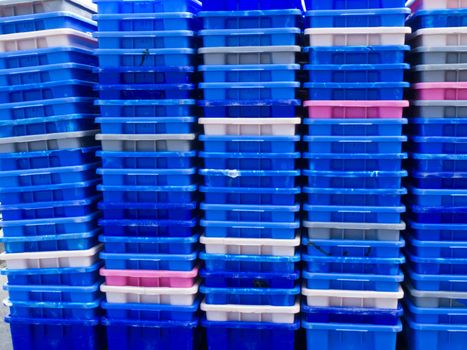 Background texture pattern of stacks of empty colorful plastic containers as used in fishery, wholesale, storage of fresh produce, cargo and retail transportation