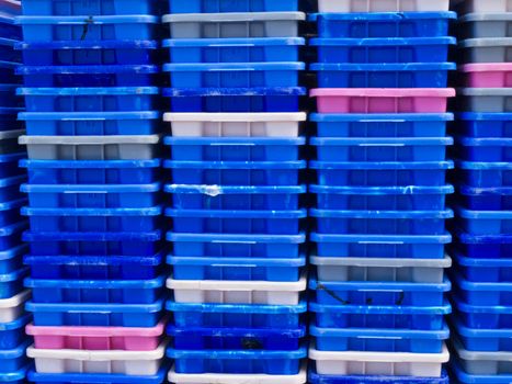 Background texture pattern of stacks of empty colorful plastic containers as used in fishery, wholesale, storage of fresh produce, cargo and retail transportation