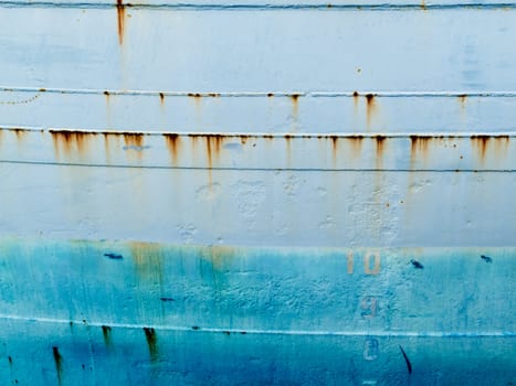 Background texture pattern of blue painted grungy steel hull of ocean ship close-up