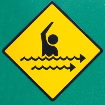 Dangerous rip current hazard symbol warning sign on wall painted green warning of seaward rip currents that can take swimmers out into the ocean